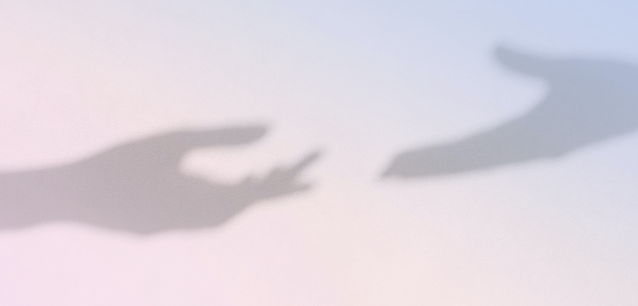 Shadows of two hands stretching towards each other on light pink blue background